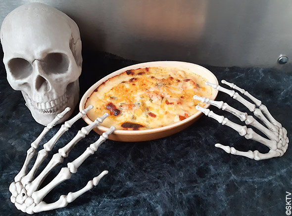 Gratin de potiron cheddar et vin blanc : le plat est tenu par un serveur-squelette d'halloween