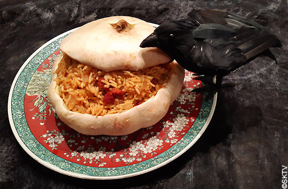 Pâtisson farci au riz pilaf et chorizo sur un plat. Notre corbeau d'halloween s'y intéresse !