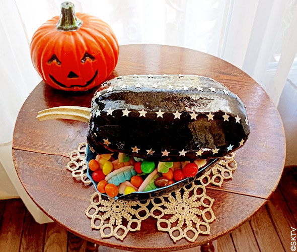 Prêts pour le trick or treat : la boîte à bonbons Halloween remplie de bonbons colorés sur un guéridon...
