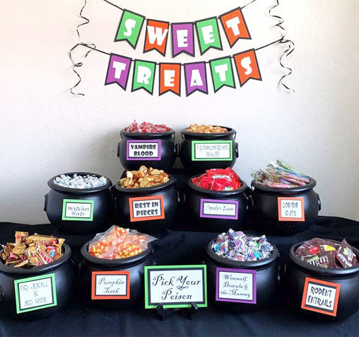 Une sweet table Halloween sous forme de candy bar avec bannière et chaudrons remplis de bonbons